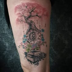 a woman's leg with a tree and clock tattoo on it