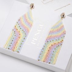 a pair of colorful beaded earrings sitting on top of a white box next to it's packaging