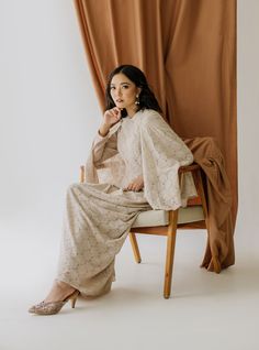 a woman is sitting on a chair and posing for the camera with her hand in her mouth