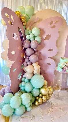 the balloon arch is decorated with pastel colors and gold accents for a butterfly themed birthday party