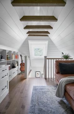 an attic bedroom with wood floors and white walls