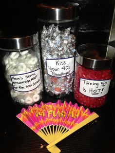 there are some candy in glass jars and a fan on the table next to them