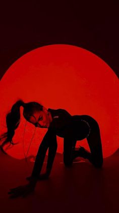 a woman kneeling down in front of a red moon