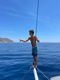 a man standing on the bow of a boat in the ocean with his arms out