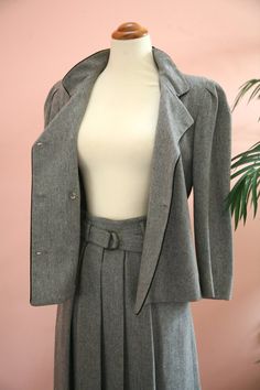 Size: Jacket size 4, Skirt size 6Material: 80% wool, 20% PolyesterLabel: Ellen TracyLadies 1970's light grey double-breasted suit features black piping,  stand up collar and original black buttons. Blazer and skirt are fully lined.  Skirt features pleats in both the front and back, side zipper and matching cloth belt.  Circa 1970's and in excellent vintage condition with no flaws.Measurements:Jacket:Bust-36 inchesAcross shoulders - 15 inchesLength - 22 inchesSleeve Length - 19 inchesSkirt:Waist Classic Tailored Wool Skirt Suit, Classic Fitted Wool Skirt Suit, Classic Long Sleeve Skirt Suit For Tailoring, Classic Spring Skirt Suit With Buttons, Wool Skirt Suit For Formal Fall Events, Wool Skirt Suit For Formal Fall Occasions, Winter Business Skirt Suit With Notch Lapel, Notch Lapel Skirt Suit For Winter Business, Tailored Wool Skirt Suit For Work