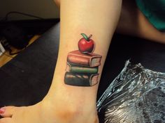 an apple and books tattoo on the ankle