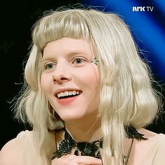 a woman with blonde hair wearing a black and white bow tie smiling at the camera