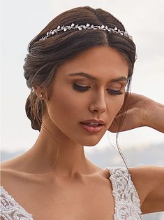 a woman wearing a tiara and holding her hair in one hand while looking down