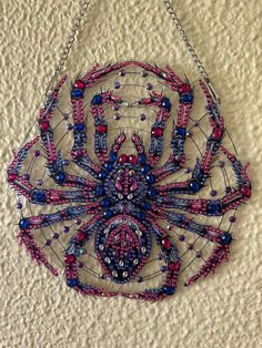 a spider made out of beads hanging on a wall