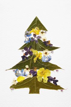 a christmas tree made out of leaves and flowers on a white background with watercolor pencils