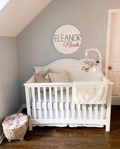 a baby's room with a white crib and gray walls, wooden floors