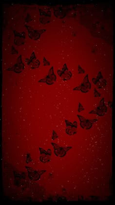 a red background with many black butterflies flying in the air on it's side