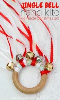 a wooden ring with bells attached to it and red ribbon around it, sitting on top of a white table