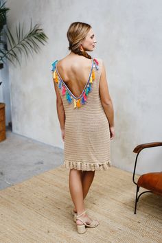 a woman in a dress is standing on a rug with her back to the camera