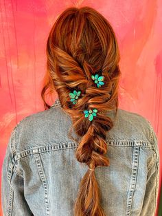 a woman with red hair and blue flowers in her hair, wearing a denim jacket