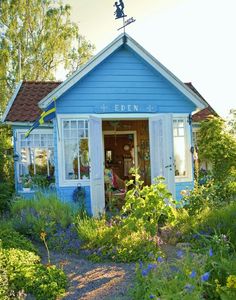 a small blue building sitting in the middle of a garden