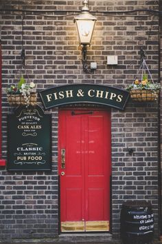 fish and chips sign above red door in front of brick building with light fixture on corner