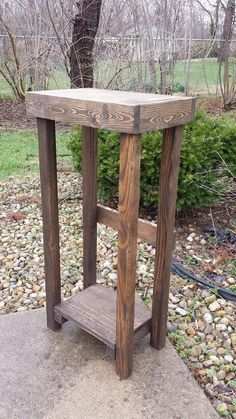 a small wooden table sitting on top of a cement slab in front of a tree