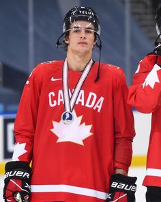 the canadian hockey player is holding his gold medal in front of him and looking off into the distance