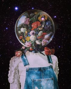 a person with overalls and flowers in their hair is standing under a glass ball