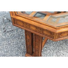 an old wooden table with glass top on the ground in front of concrete flooring