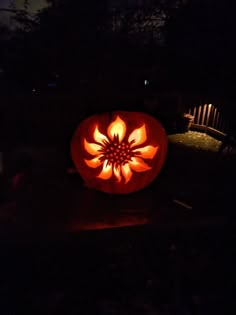 a pumpkin carved to look like a flower is lit up in the dark at night