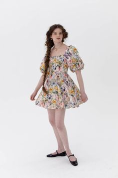 This mini version of our classic Day Dress features a romantic backdrop of lilacs and bluebells, embellished by a kaleidoscope of butterfly wings. It features a comfortable cotton cut with curve-hugging princess seams, voluminous puff sleeves, and an adjustable tie at the bust. Crafted entirely from cotton, this dress remains cool and crisp, ensuring maximum comfort. Cotton poplin mini dress with puff sleeves and curve-hugging princess seams Adjustable bust tie Invisible zipper closure To ensure Spring Multicolor Puff Sleeve Mini Dress, Multicolor Puff Sleeve Mini Dress For Spring, Cotton Mini Dress With Floral Print And Puff Sleeves, Cotton Mini Dress With Floral Print And Square Neck, Feminine Cotton Mini Dress For Garden Party, Cotton Floral Mini Dress For Daywear, Feminine Fitted Cotton Floral Dress, Cotton Mini Dress For Garden Party, Cotton Puff Sleeve Dress For Spring