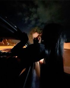 a man and woman are sitting in the back seat of a car at night, talking on their cell phones