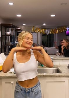 a woman standing in front of a kitchen counter holding a plate with the word love on it