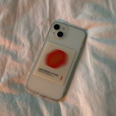 an iphone case sitting on top of a bed covered in white sheets and red circles