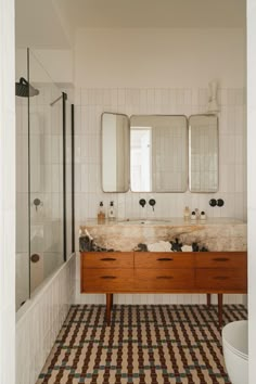 a bathroom with two sinks, mirrors and tiled flooring in the shower stall area