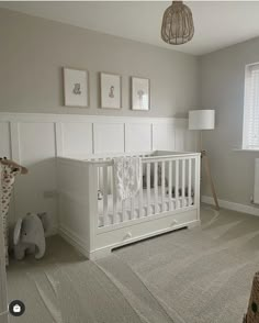 a baby's room with a crib, lamp and pictures on the wall