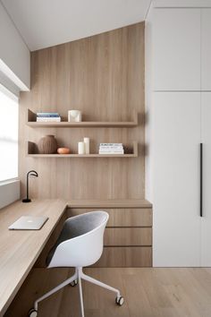 a white chair sitting in front of a desk next to a wooden shelf filled with books