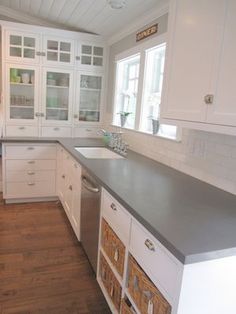 a kitchen with white cabinets and gray counter tops