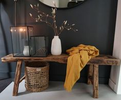 a wooden table topped with a vase filled with flowers next to a mirror and lantern