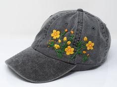 a gray hat with yellow flowers embroidered on it