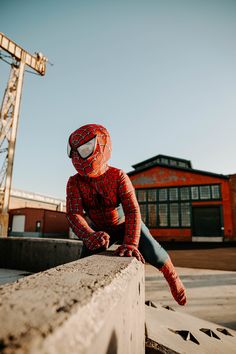 a spider man sitting on top of a cement wall