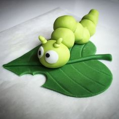 a close up of a cake shaped like a caterpillar on a green leaf