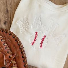 a baseball mitt and t - shirt sitting on a wooden floor next to each other