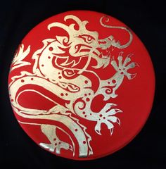 a red and gold plate with a dragon on it's side, against a black background