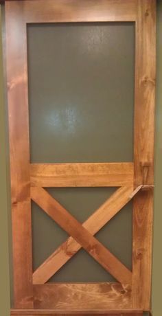 a wooden door with a green wall in the background and wood trimming on it