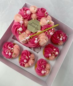 cupcakes with pink frosting and flowers in a box