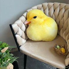 a yellow bird sitting on top of a chair next to a basket filled with eggs