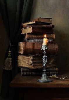 a stack of books with a lit candle on top