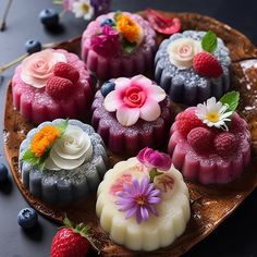 several desserts are arranged on a plate with berries and flowers in the center, including raspberries