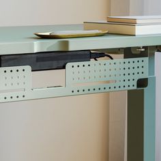 a laptop computer sitting on top of a desk next to a stack of books and a plate