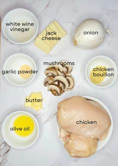 ingredients to make chicken broth laid out on a marble counter top with white wine, vinegar, cheese, mushrooms, garlic, and butter