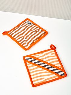 two orange and white striped bibs sitting on top of a table next to each other