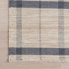 an area rug with blue and white plaid pattern on top of a wooden flooring surface