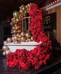 red flowers and gold balls are on display in front of a white bathtub with a birdcage